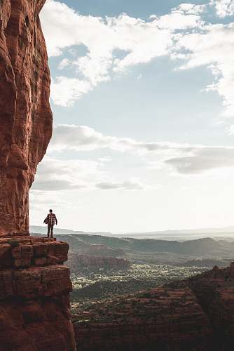 leisure activities man standing on cliff during cloudy day sport